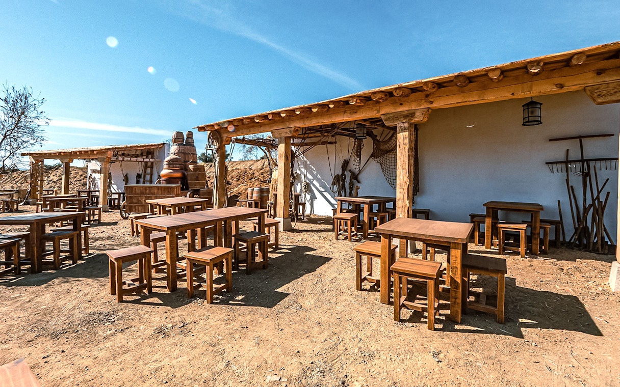Outdoor seating area at Puy du Fou España park with rustic wooden tables and chairs.