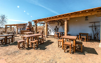 Outdoor seating area at Puy du Fou España park with rustic wooden tables and chairs.