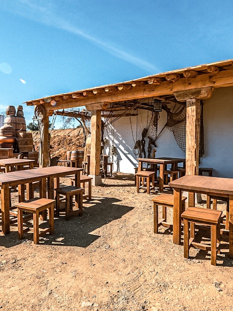 Outdoor seating area at Puy du Fou España park with rustic wooden tables and chairs.