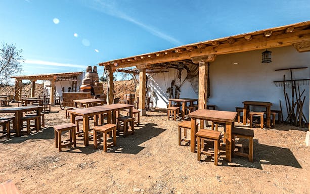 Outdoor seating area at Puy du Fou España park with rustic wooden tables and chairs.