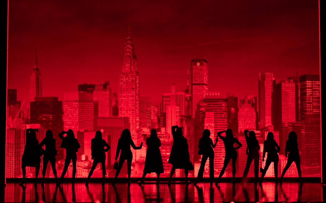 Silhouettes of performers on stage with New York City skyline backdrop during The Devil Wears Prada Westend show.