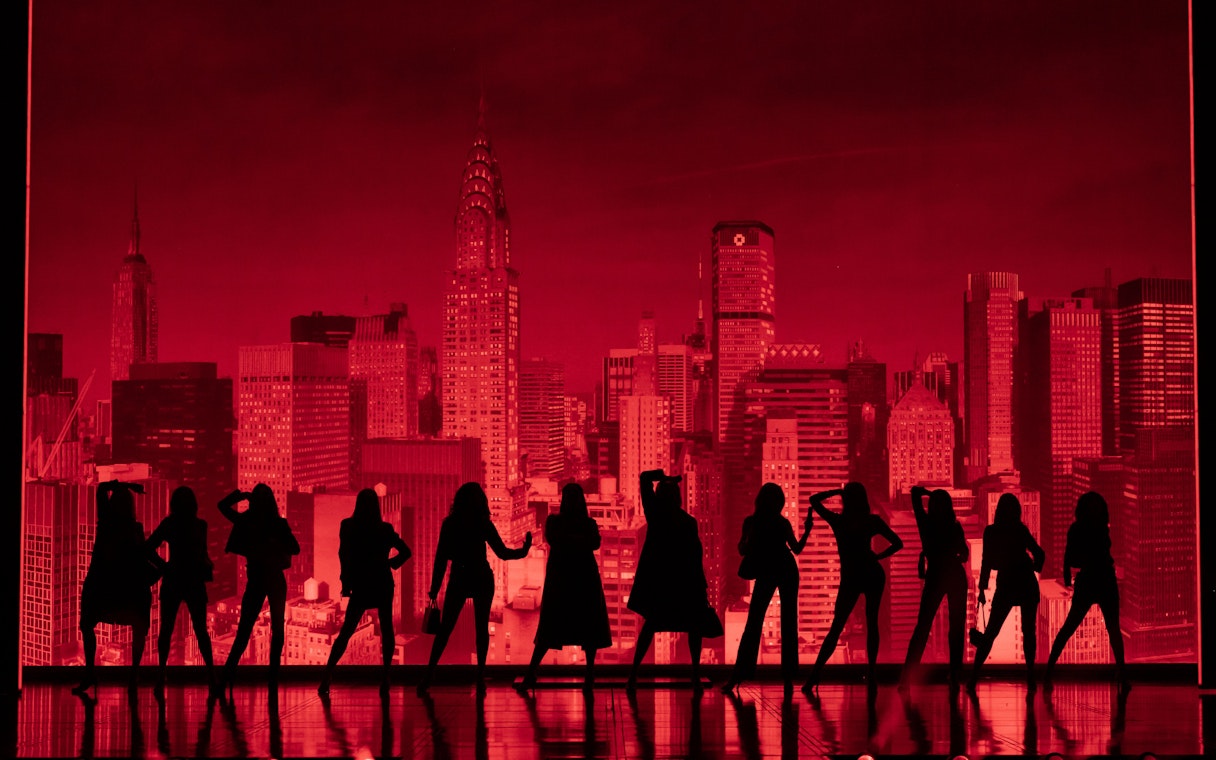 Silhouettes of performers on stage with New York City skyline backdrop during The Devil Wears Prada Westend show.