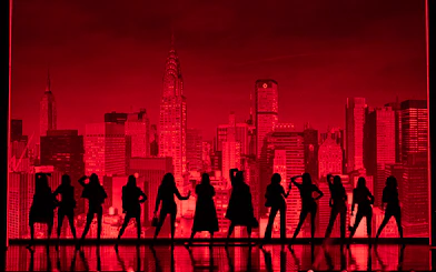 Silhouettes of performers on stage with New York City skyline backdrop during The Devil Wears Prada Westend show.