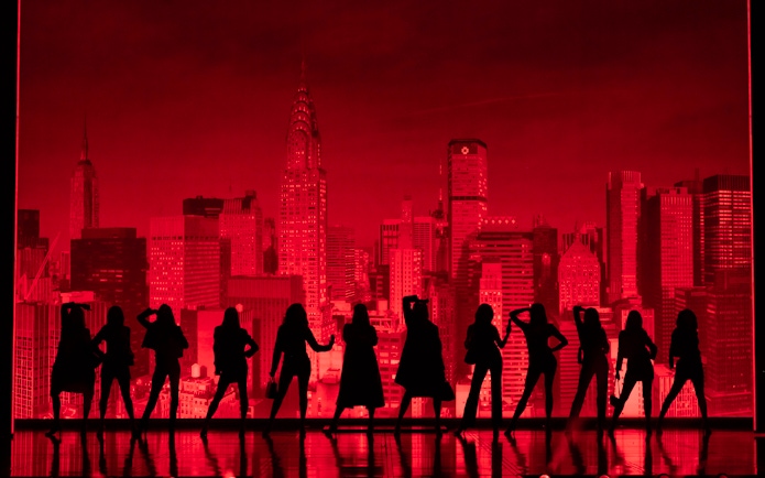 Silhouettes of performers on stage with New York City skyline backdrop during The Devil Wears Prada Westend show.