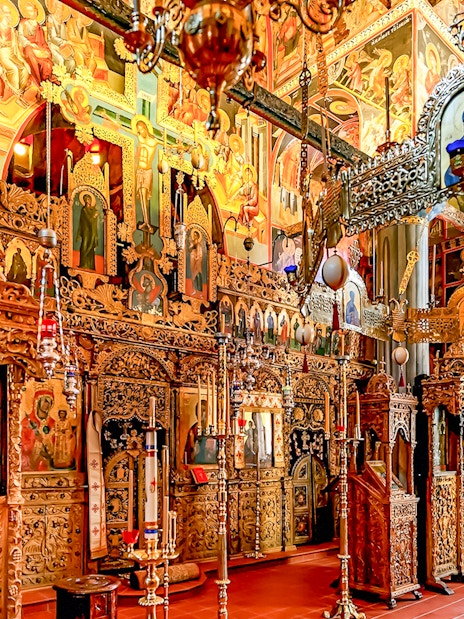 Interior of The Monastery of Great Meteoron with ornate religious icons and wooden carvings.