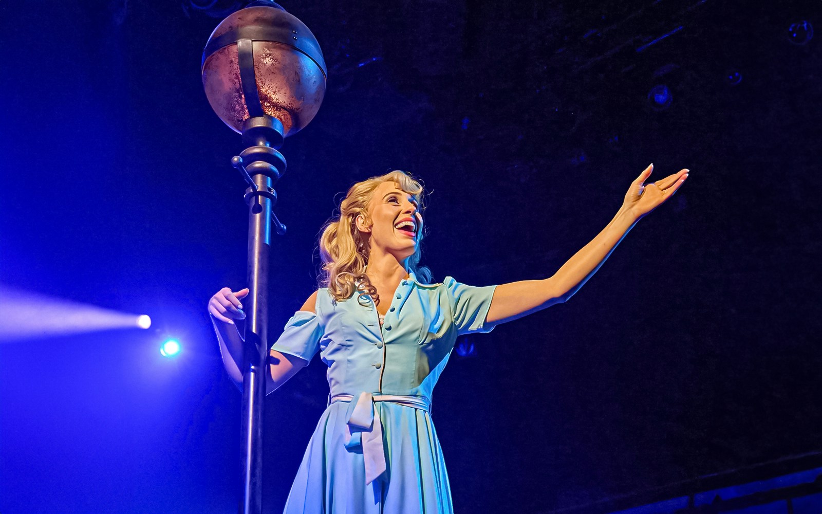 Performer in blue dress on stage during Guys & Dolls musical.