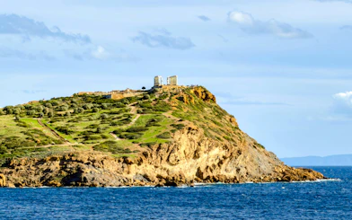Cape Sounio with Poseidon Temple on hilltop overlooking the Aegean Sea.