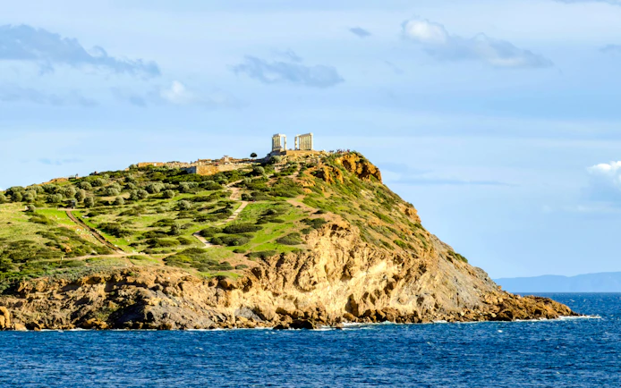 Cape Sounio with Poseidon Temple on hilltop overlooking the Aegean Sea.
