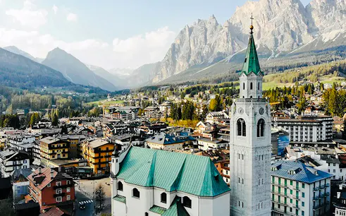 Cortina d'Ampezzo town with church tower and Dolomites mountains, seen on a full-day tour from Venice.