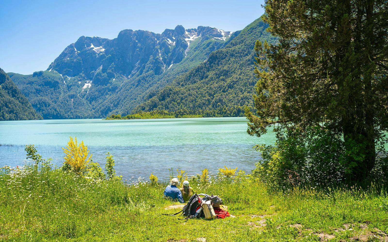 Visitors relaxing by Nahuel Huapi Lake with mountain views near Puerto Blest, Patagonia.