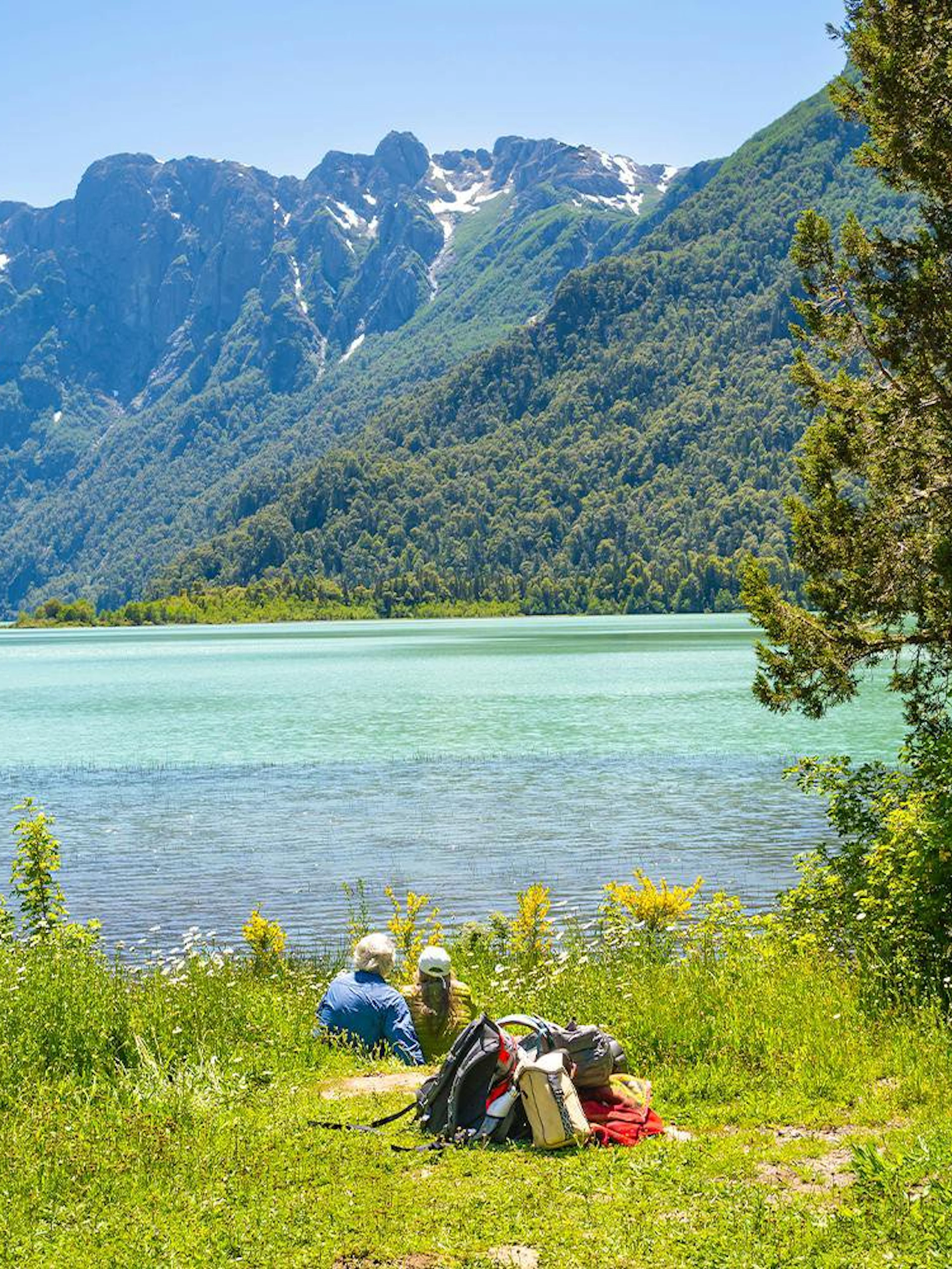 Visitors relaxing by Nahuel Huapi Lake with mountain views near Puerto Blest, Patagonia.