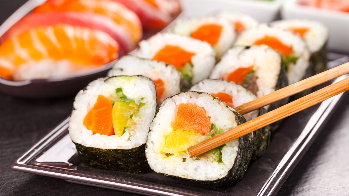 Sushi pieces with chopsticks on a plate, close-up view.