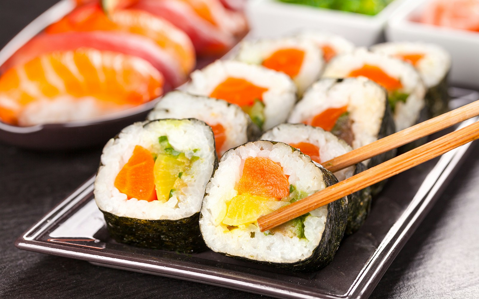 Sushi pieces with chopsticks on a plate, close-up view.