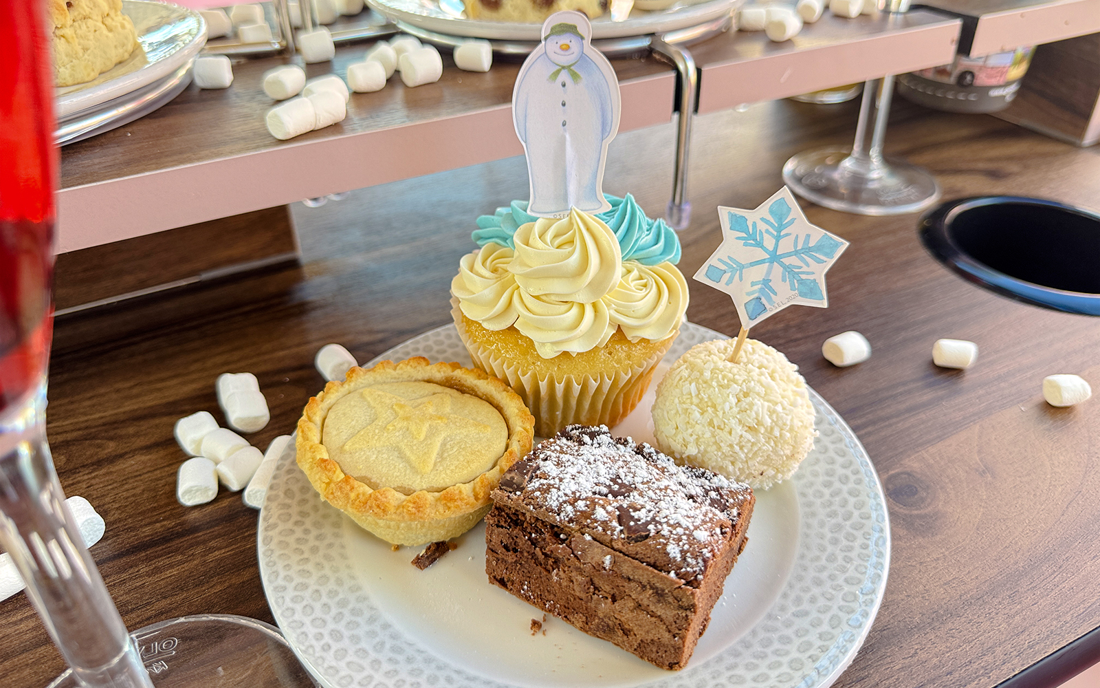 Cupcake with snowman topper, mince pie, brownie, and coconut treat on The Snowman Afternoon Tea Bus.