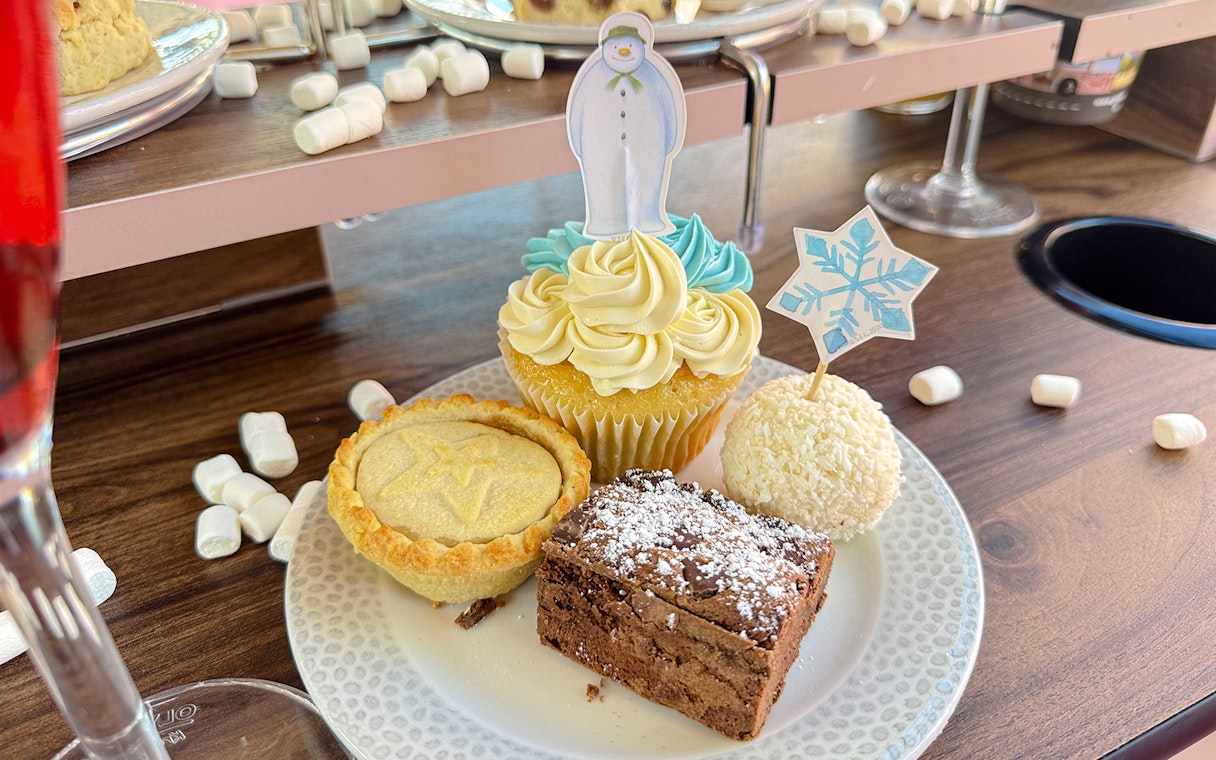 Cupcake with snowman topper, mince pie, brownie, and coconut treat on The Snowman Afternoon Tea Bus.