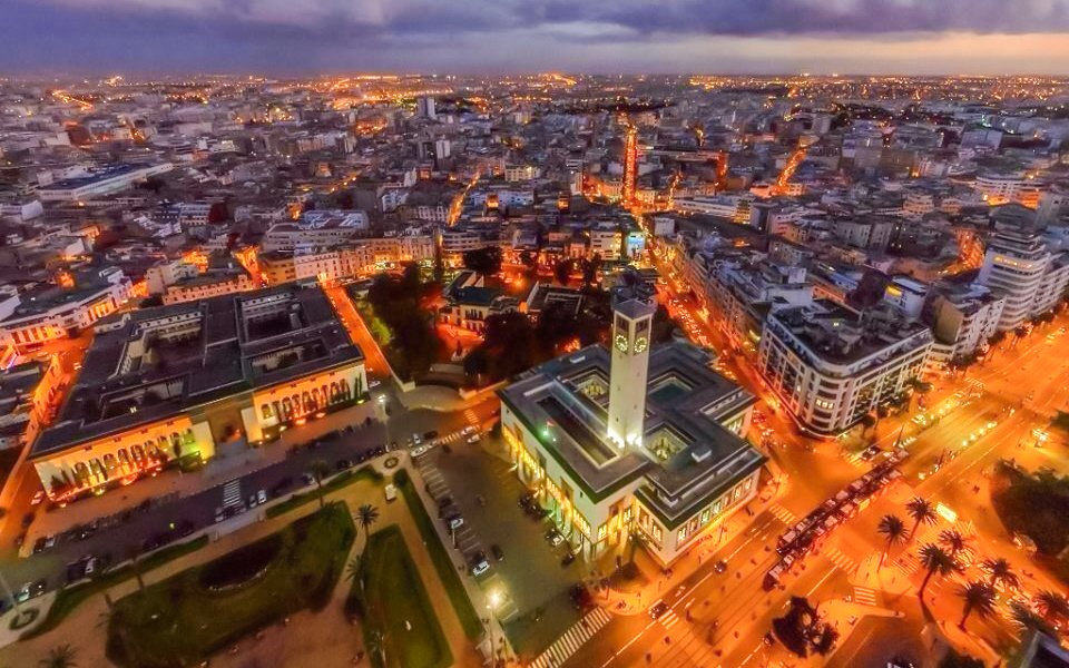Aerial night view of illuminated Hassan II Mosque and Casablanca cityscape, Morocco.