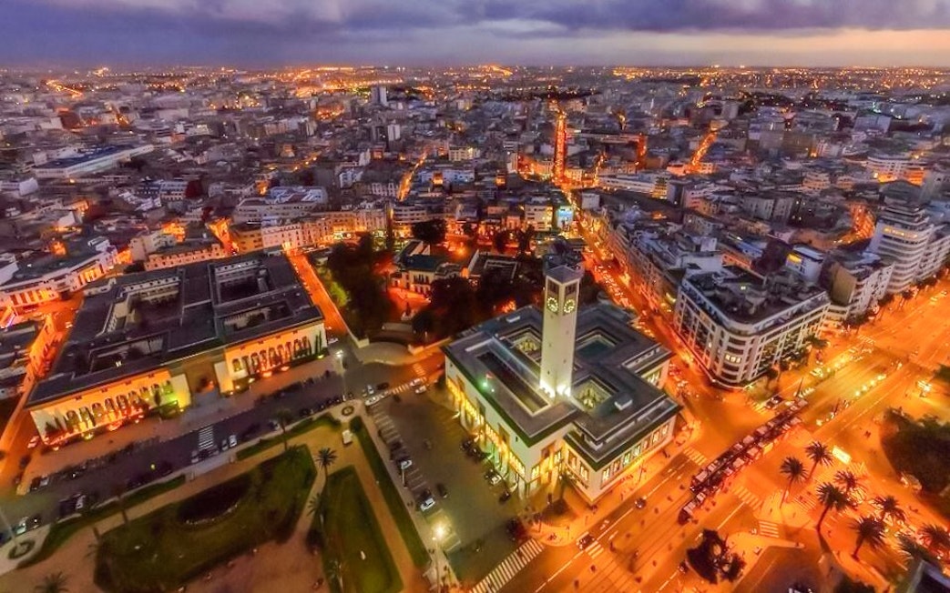 Aerial night view of illuminated Hassan II Mosque and Casablanca cityscape, Morocco.