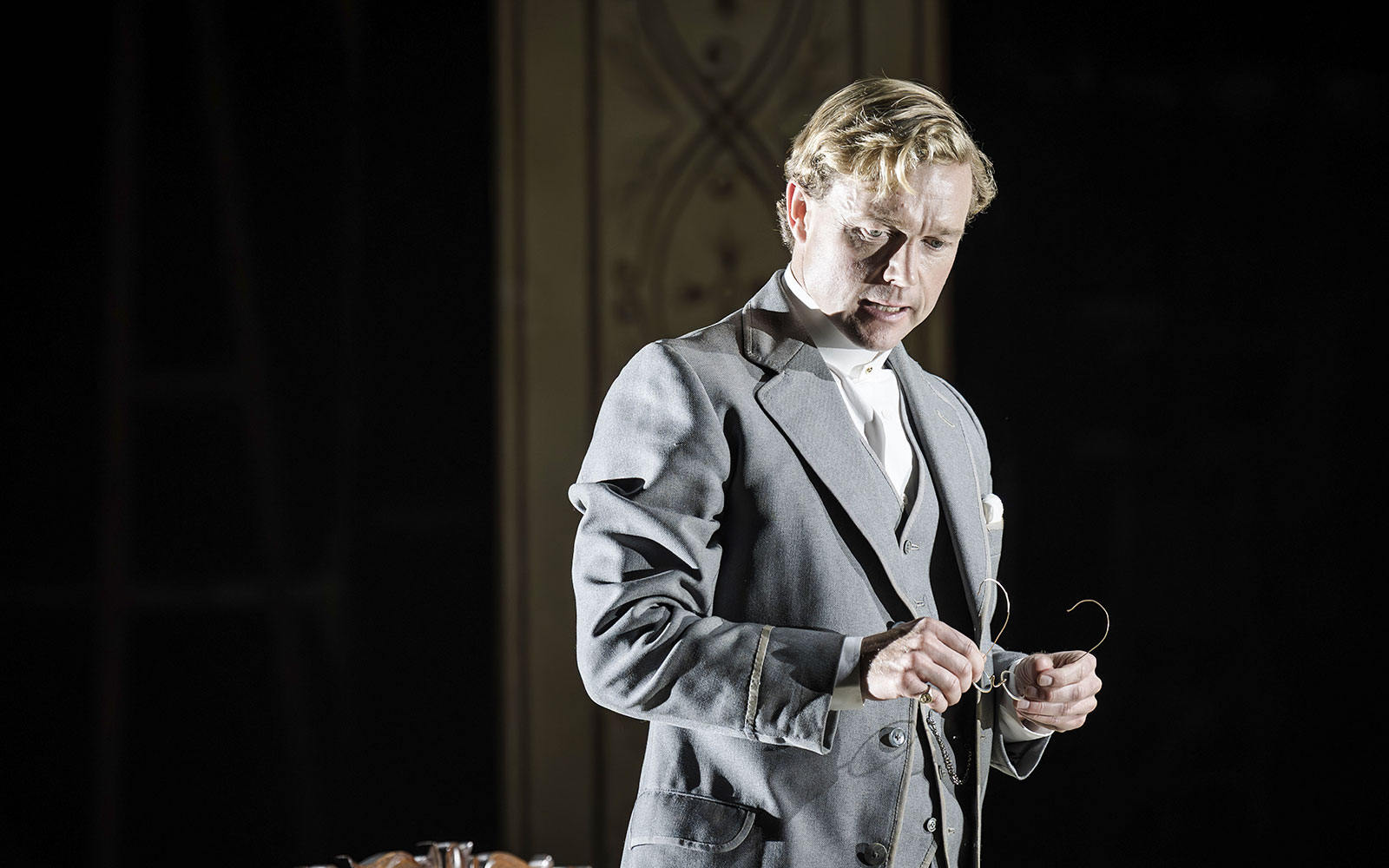 Performer in Grace Pervades West End show holding glasses on stage.