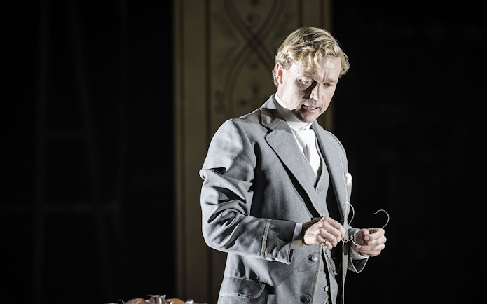 Performer in Grace Pervades West End show holding glasses on stage.