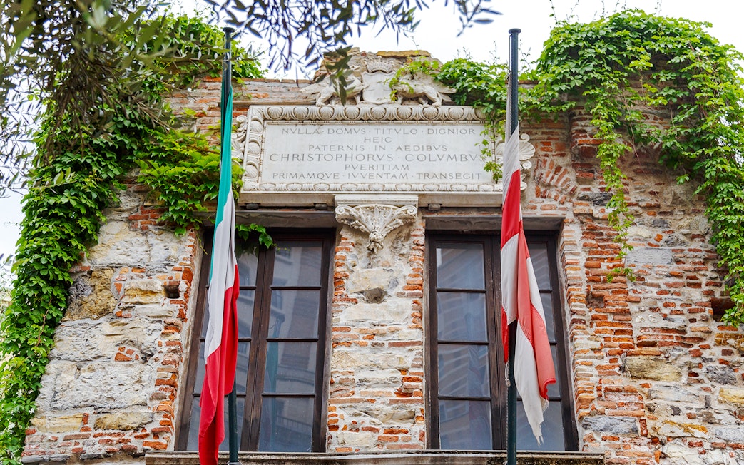 Christopher Columbus' House facade with Italian flags and ivy-covered brickwork.