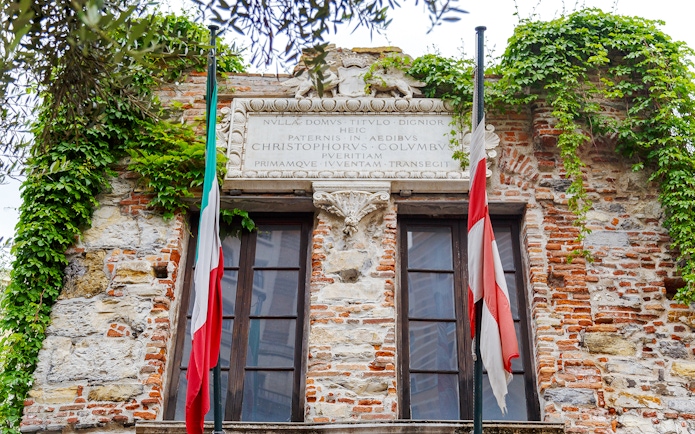 Christopher Columbus' House facade with Italian flags and ivy-covered brickwork.