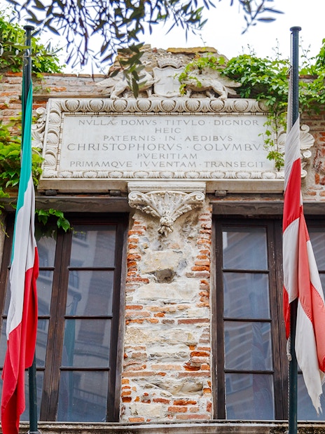 Christopher Columbus' House facade with Italian flags and ivy-covered brickwork.