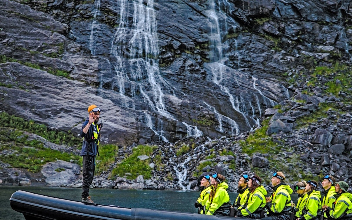 Tourists on a RIB boat near Hellesylt waterfall during a Geiranger fjord safari.