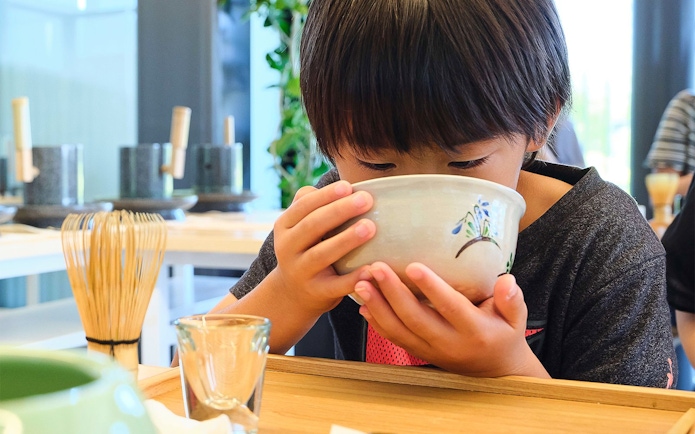 Child enjoying matcha tea in a traditional setting.