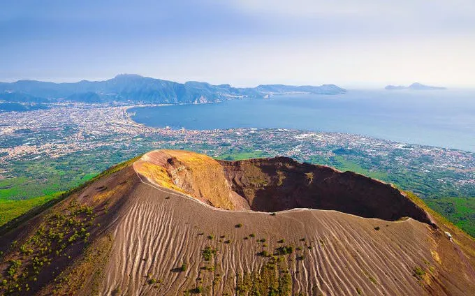 Aerial view of Mount Vesuvius crater with Naples and coastline in the background, Italy.