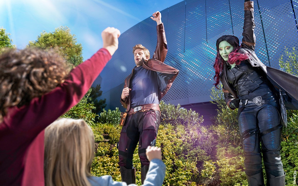 Characters in costume interacting with children at a theme park attraction.