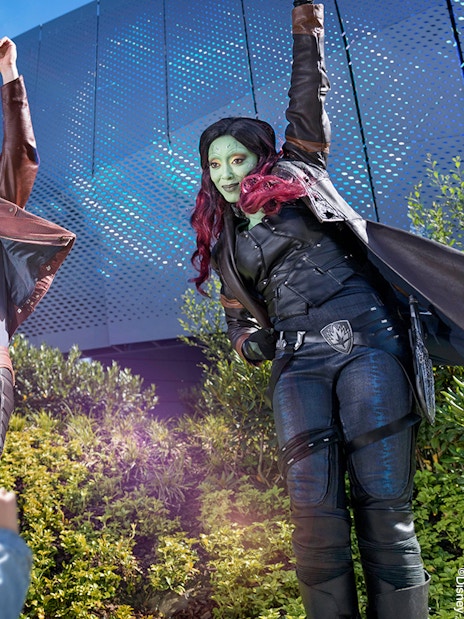 Characters in costume interacting with children at a theme park attraction.