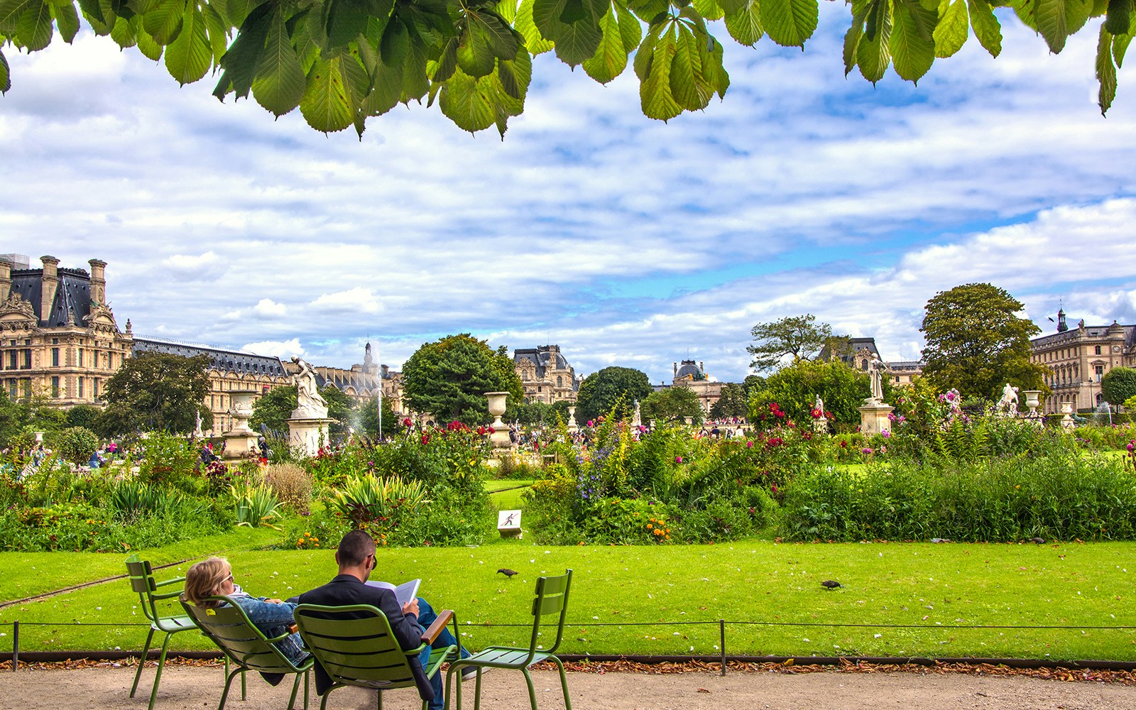 Visitors enjoying a sunny day at the Tuileries Garden, Paris, featuring beautiful greenery and historical statues