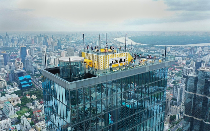 Mahanakhon SkyWalk rooftop view in Bangkok with cityscape in the background.