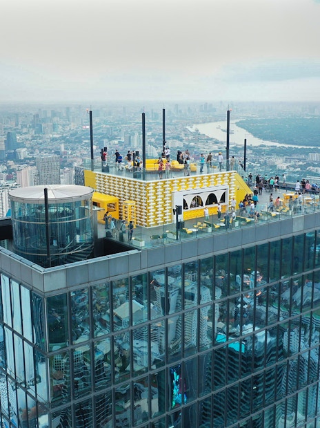 Mahanakhon SkyWalk rooftop view in Bangkok with cityscape in the background.