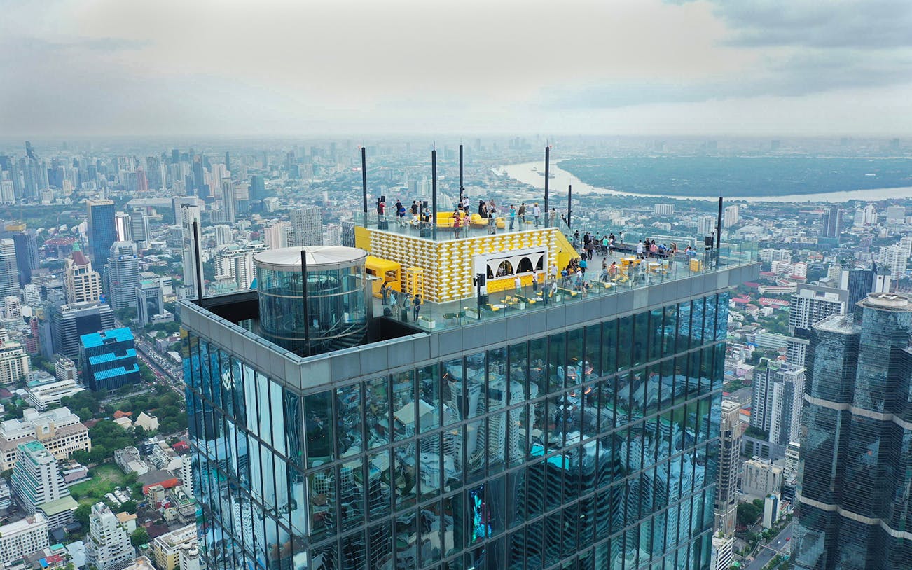 Mahanakhon SkyWalk rooftop view in Bangkok with cityscape in the background.