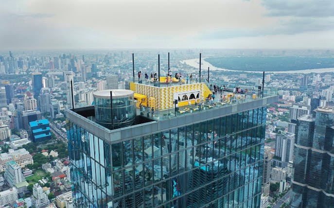 Mahanakhon SkyWalk rooftop view in Bangkok with cityscape in the background.
