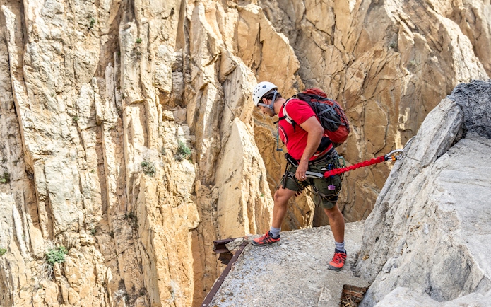 Man rappelling down Caminito del Rey in safety gear, Spain.