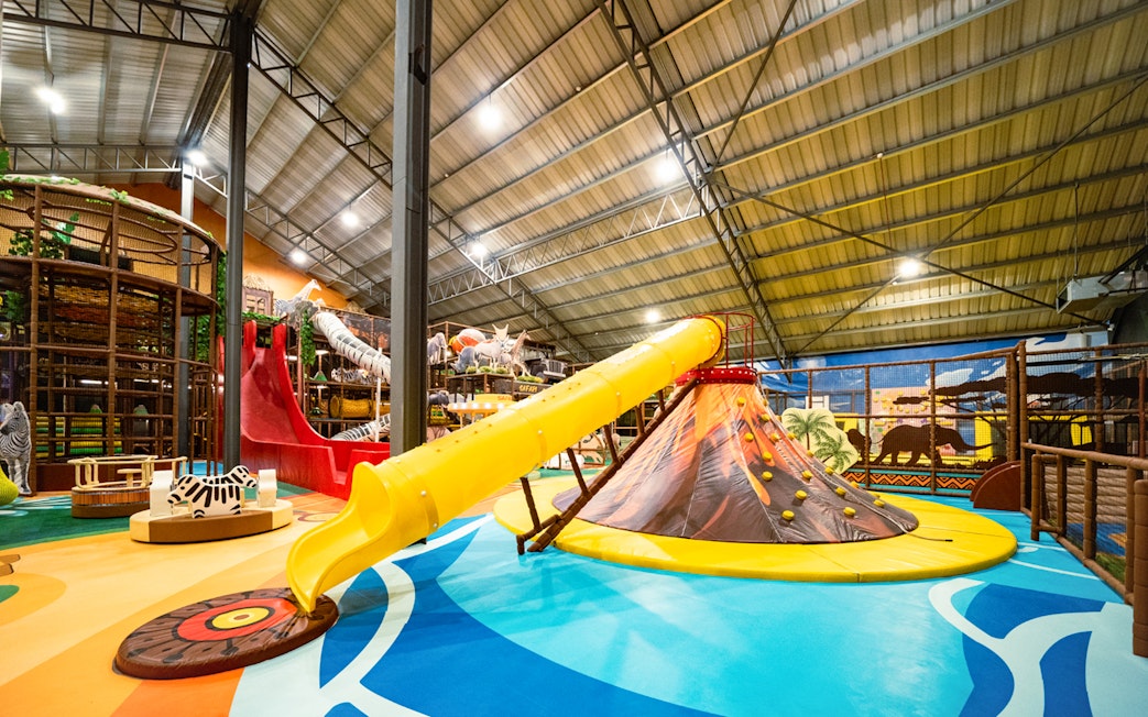 Indoor safari playland with a yellow slide and animal-themed decor.