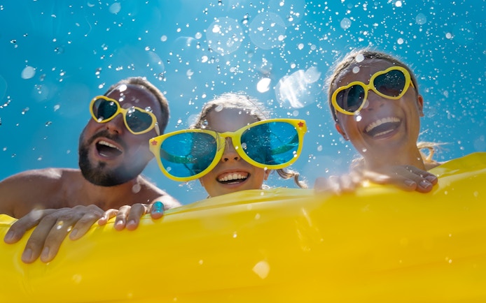 Family enjoying a water ride at Aqualand, wearing colorful sunglasses.