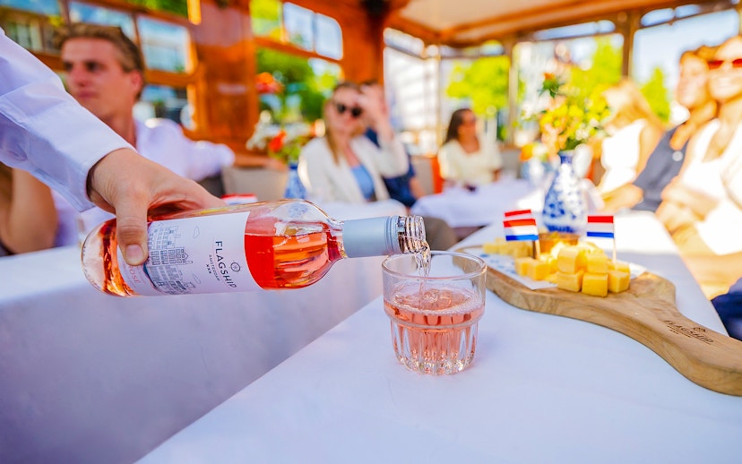 Wine being poured into a glass with cheese platter on a luxury cruise in Amsterdam.