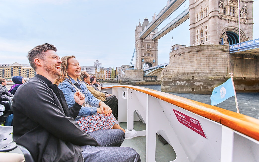 Tourists enjoying a boat ride near Tower Bridge, London on Big Bus: Big Day Out.