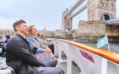 Tourists enjoying a boat ride near Tower Bridge, London on Big Bus: Big Day Out.