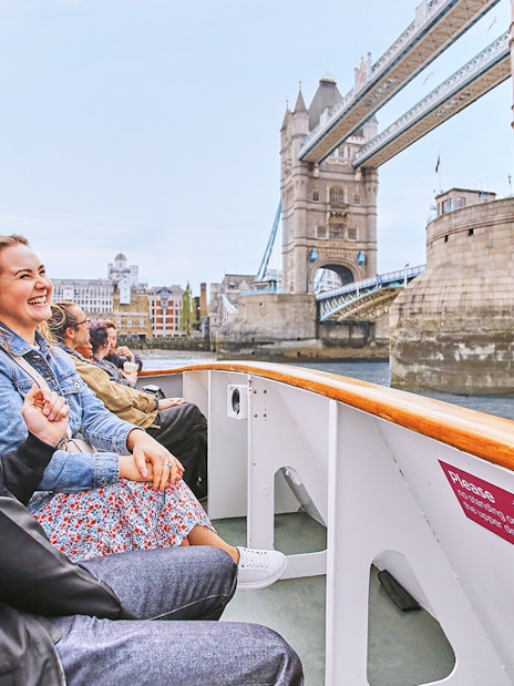 Tourists enjoying a boat ride near Tower Bridge, London on Big Bus: Big Day Out.