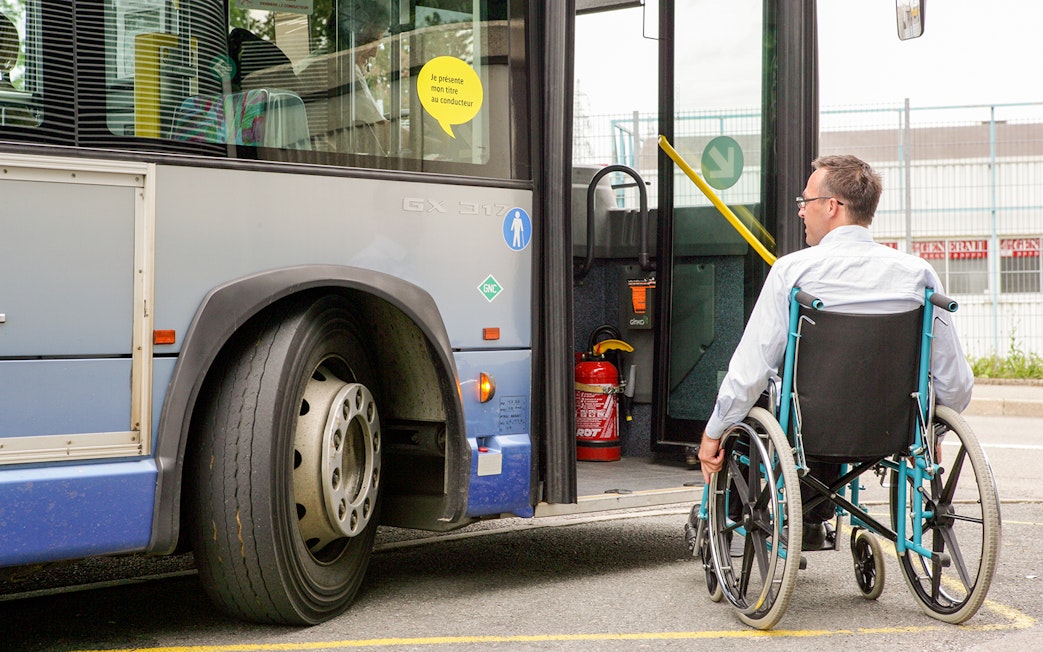 Man in wheelchair boarding a bus via accessible ramp.