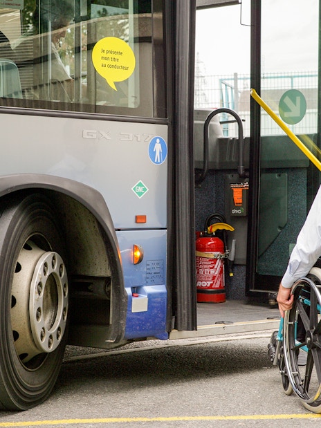 Man in wheelchair boarding a bus via accessible ramp.