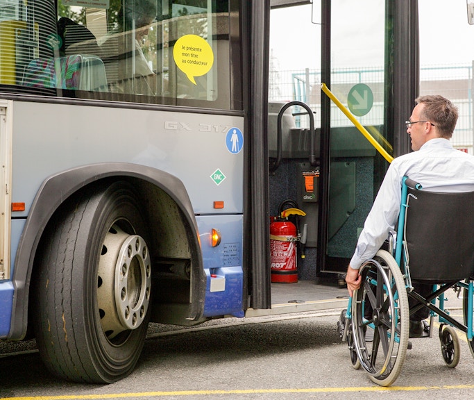 Man in wheelchair boarding a bus via accessible ramp.
