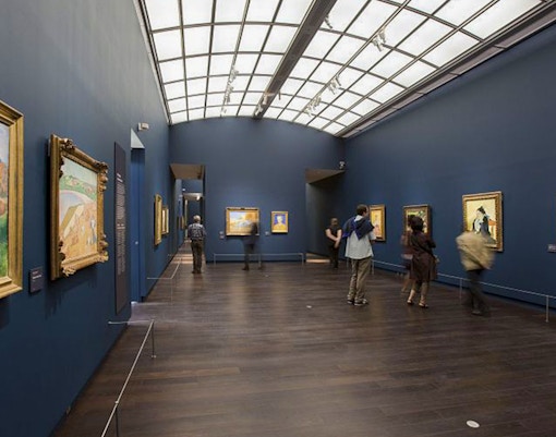 Visitors exploring art at Orsay Museum, Paris, during a guided tour focused on Impressionist masterpieces.