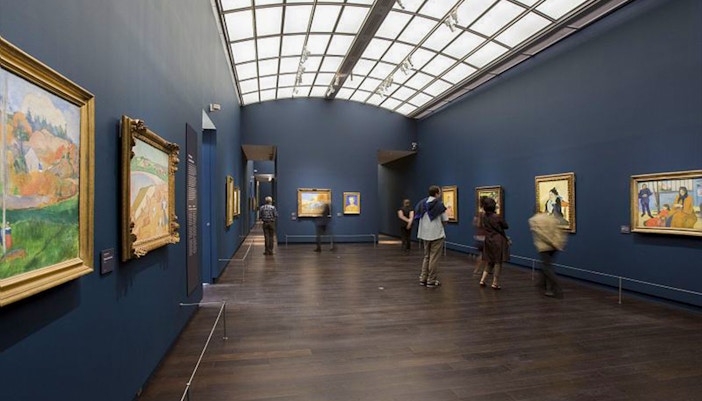 Visitors exploring art at Orsay Museum, Paris, during a guided tour focused on Impressionist masterpieces.