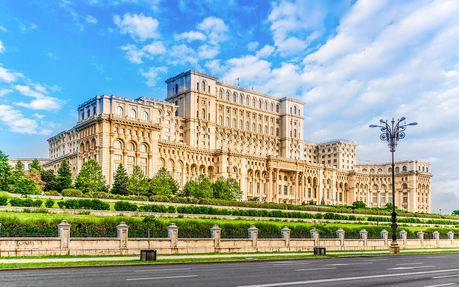 Romanian Parliament building in Bucharest with gardens and clear sky.