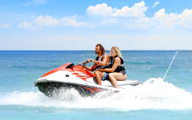 Guests jet skiing on clear blue waters near Dubai skyline.